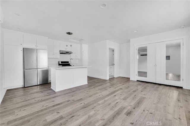 kitchen with french doors, a center island with sink, light hardwood / wood-style flooring, white cabinetry, and built in fridge