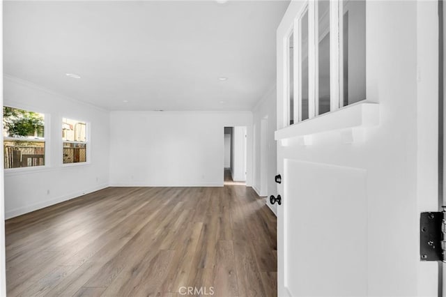 unfurnished living room featuring hardwood / wood-style flooring and ornamental molding