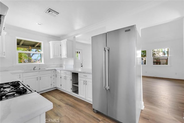 kitchen with white cabinetry, high end refrigerator, sink, and light hardwood / wood-style floors