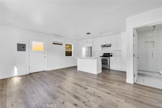 unfurnished living room featuring a wall unit AC, electric panel, and light hardwood / wood-style floors