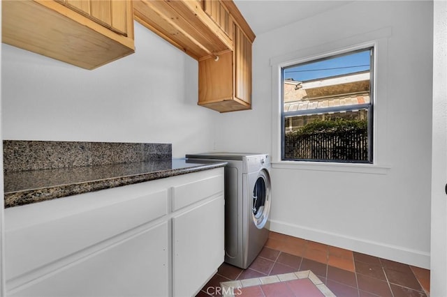 clothes washing area featuring dark tile patterned flooring, cabinets, and washer / dryer