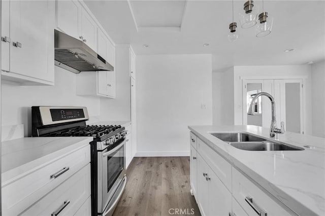 kitchen with stainless steel range with gas cooktop, sink, light wood-type flooring, light stone counters, and white cabinetry