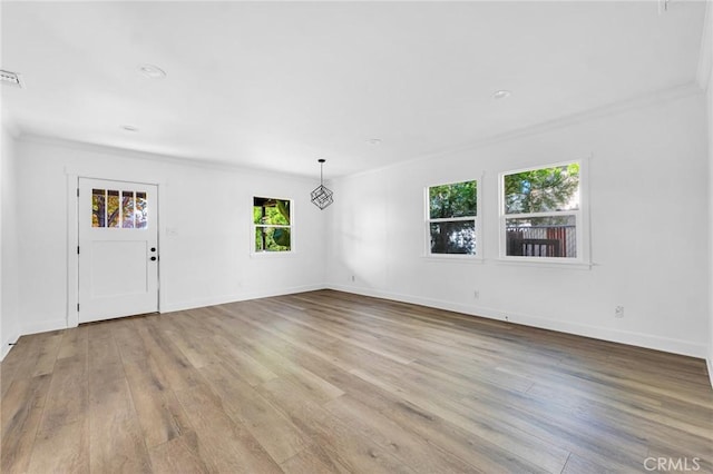 interior space with light wood-type flooring, crown molding, and a healthy amount of sunlight