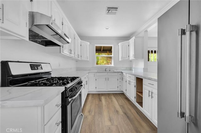 kitchen featuring light stone countertops, white cabinetry, sink, stainless steel appliances, and light hardwood / wood-style floors