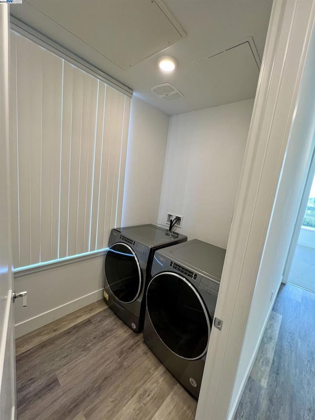 washroom featuring washing machine and clothes dryer and light hardwood / wood-style flooring