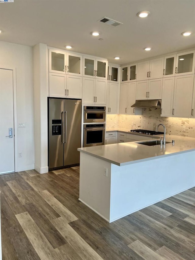 kitchen featuring white cabinetry, dark wood-type flooring, tasteful backsplash, kitchen peninsula, and appliances with stainless steel finishes