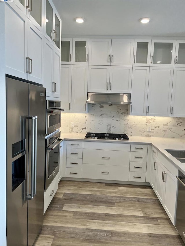 kitchen featuring backsplash, stainless steel appliances, sink, light hardwood / wood-style flooring, and white cabinets