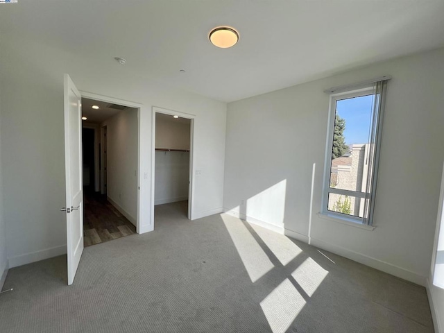 unfurnished bedroom featuring a spacious closet, carpet floors, and a closet