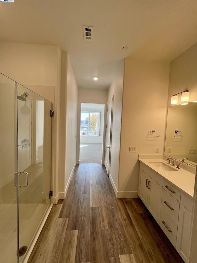 bathroom with hardwood / wood-style flooring, vanity, and an enclosed shower