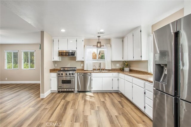 kitchen featuring plenty of natural light, white cabinets, and high end appliances