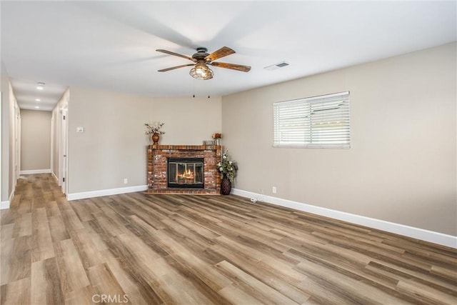 unfurnished living room featuring a fireplace, light hardwood / wood-style flooring, and ceiling fan