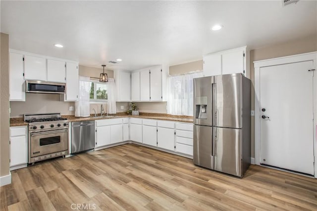 kitchen featuring white cabinets, appliances with stainless steel finishes, light wood-type flooring, and hanging light fixtures