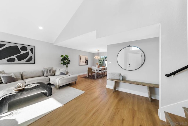 living room with light wood-type flooring, vaulted ceiling, and a notable chandelier