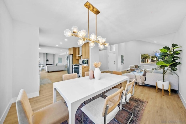 dining area with vaulted ceiling, light hardwood / wood-style floors, and a notable chandelier