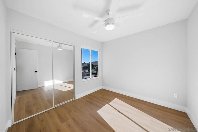 unfurnished bedroom featuring ceiling fan, a closet, and hardwood / wood-style floors