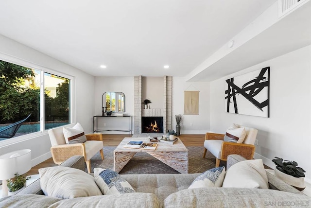 living room featuring wood-type flooring and a brick fireplace