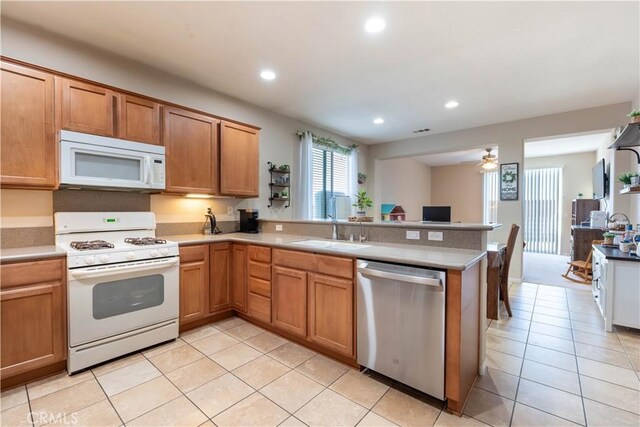 kitchen with sink, light tile patterned floors, ceiling fan, kitchen peninsula, and white appliances