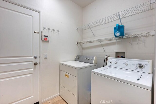 laundry area with separate washer and dryer and light tile patterned floors