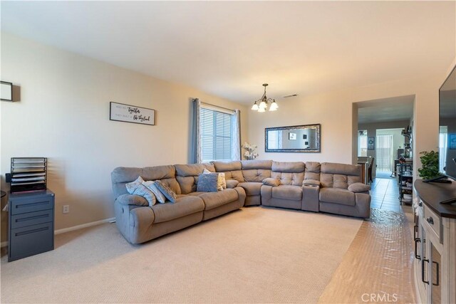 living room featuring an inviting chandelier, light colored carpet, and plenty of natural light