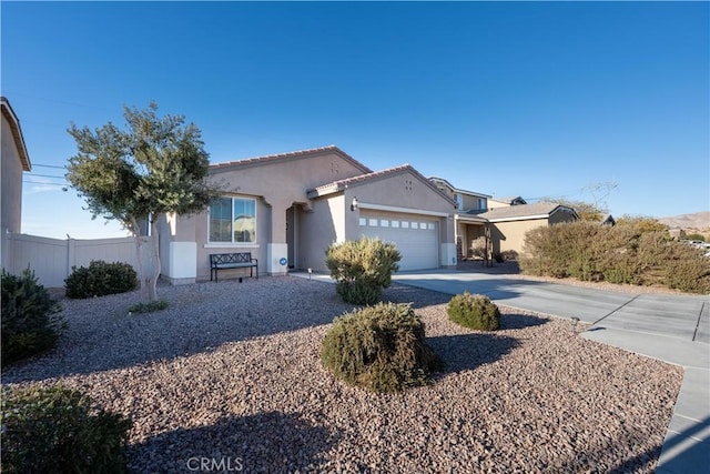 view of front of house with fence, a tiled roof, stucco siding, a garage, and driveway