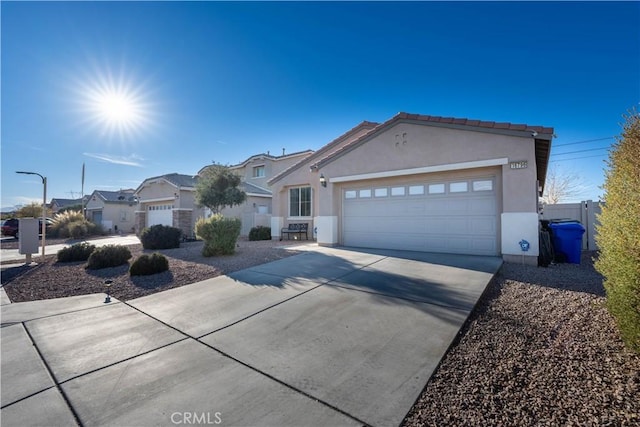 view of front of home featuring stucco siding, driveway, a garage, and fence