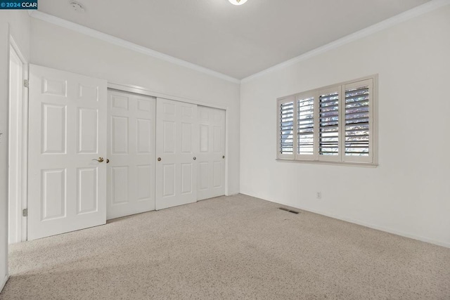 unfurnished bedroom with carpet flooring, a closet, and ornamental molding