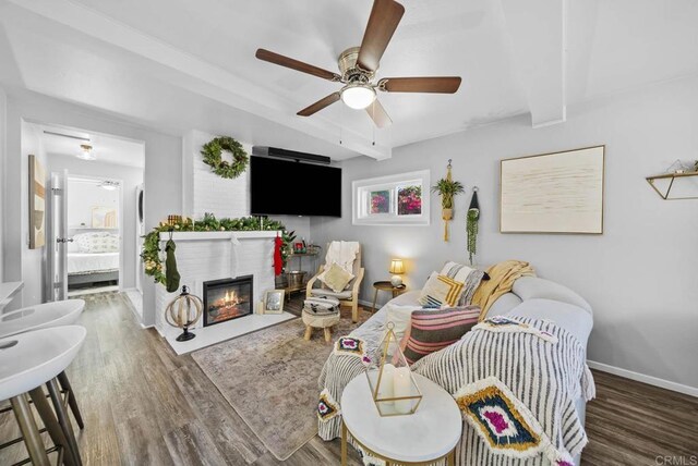 living room with beam ceiling, a wealth of natural light, ceiling fan, and dark wood-type flooring