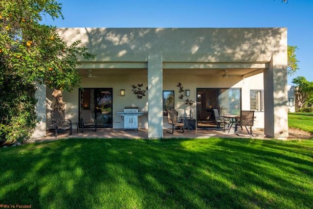 rear view of house with ceiling fan, a yard, and a patio