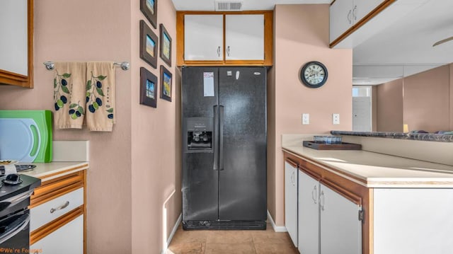 kitchen with black fridge with ice dispenser, white cabinets, and light tile patterned floors