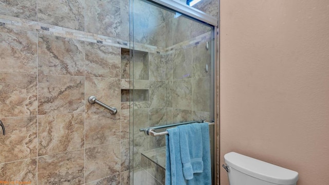 bathroom featuring toilet and a shower with shower door