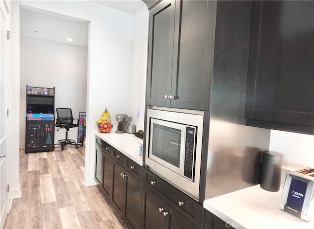 kitchen featuring dark brown cabinets, light hardwood / wood-style floors, and stainless steel microwave