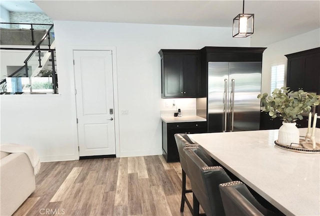 kitchen with built in fridge, hanging light fixtures, and light hardwood / wood-style floors