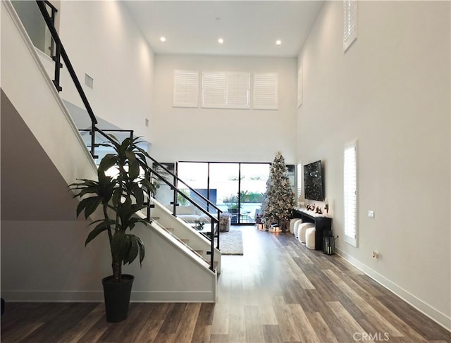 staircase with a towering ceiling and hardwood / wood-style flooring