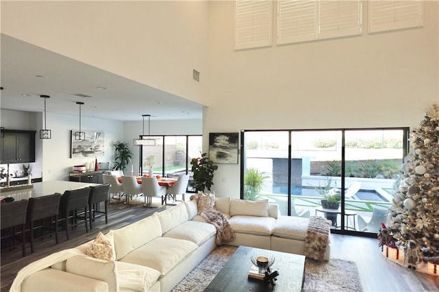 living room with a towering ceiling and dark wood-type flooring