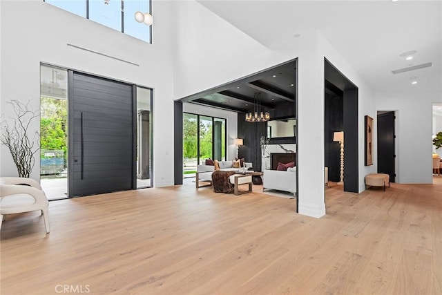 entryway featuring an inviting chandelier, a premium fireplace, a high ceiling, and light hardwood / wood-style flooring