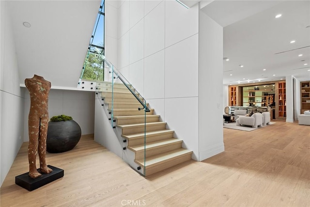 staircase with hardwood / wood-style flooring and a high ceiling