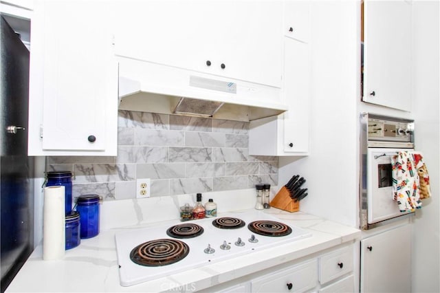 kitchen with light stone counters, backsplash, white appliances, and white cabinets