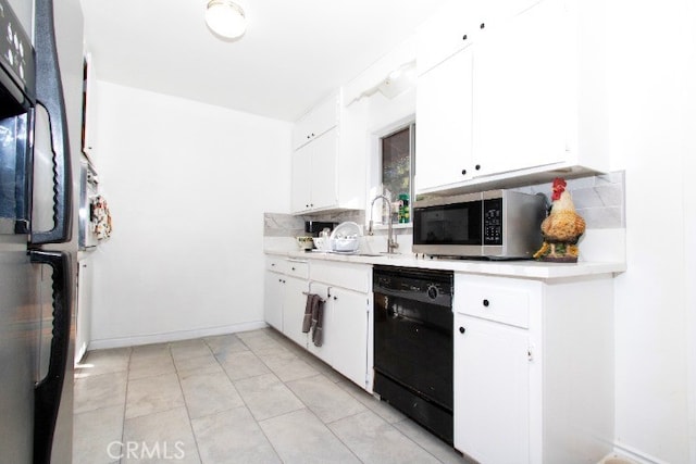 kitchen with black dishwasher, backsplash, white cabinetry, and fridge