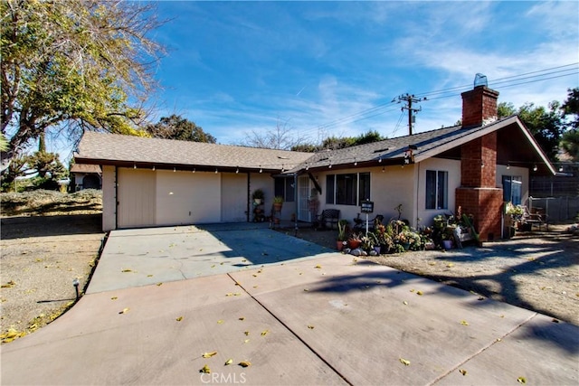 single story home with concrete driveway, a garage, a chimney, and stucco siding