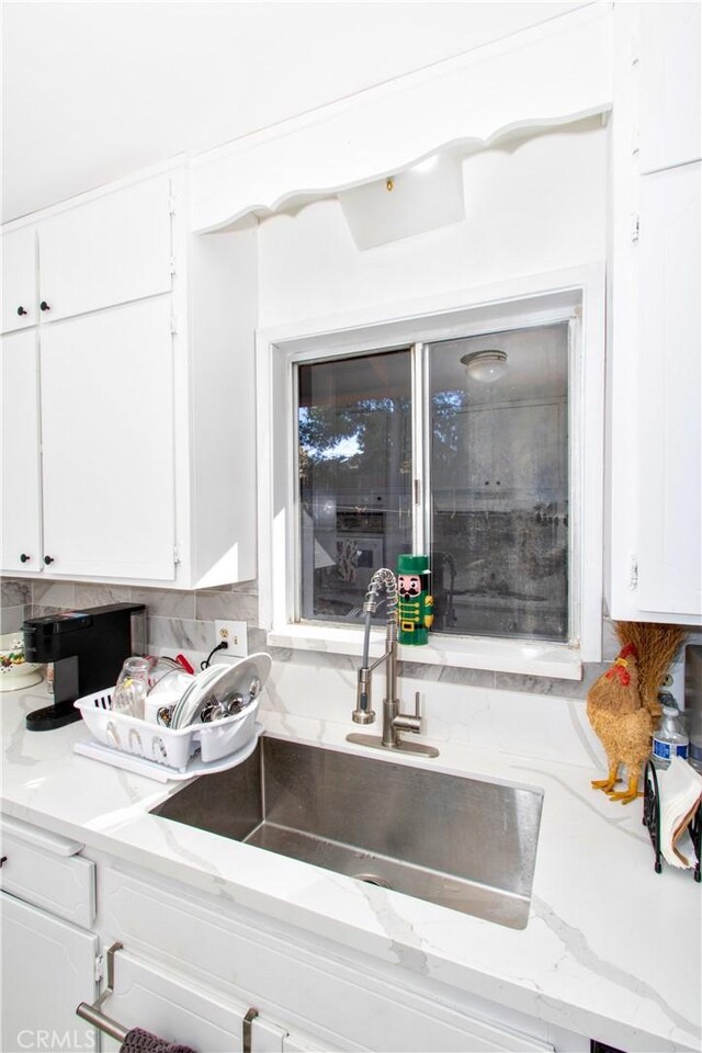 details featuring white cabinets, light stone counters, and sink