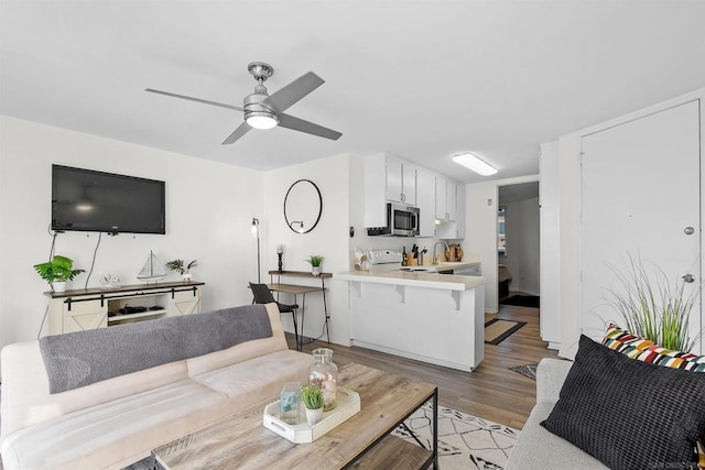 living room with light hardwood / wood-style flooring, ceiling fan, and sink