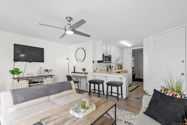 living room featuring light hardwood / wood-style flooring, ceiling fan, and sink