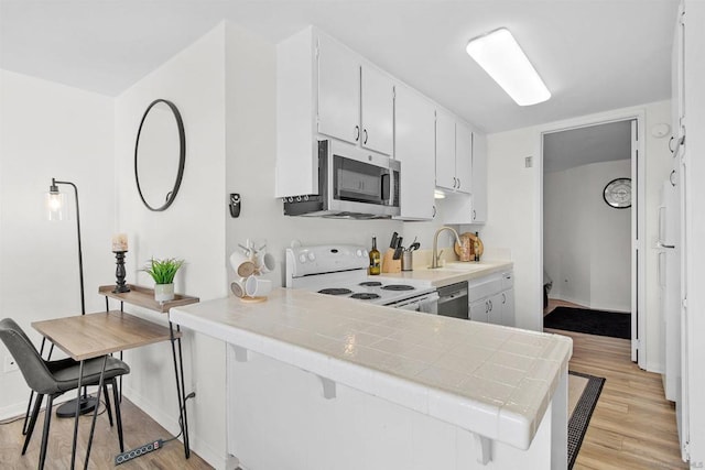 kitchen featuring white cabinetry, stainless steel appliances, light hardwood / wood-style flooring, kitchen peninsula, and tile countertops