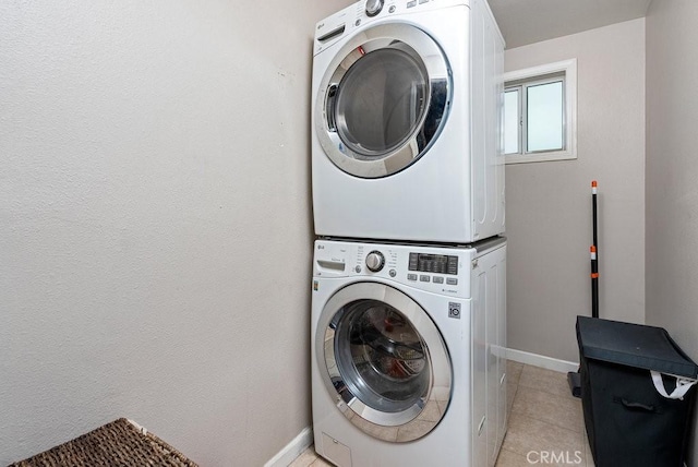 clothes washing area with light tile patterned flooring and stacked washer and clothes dryer