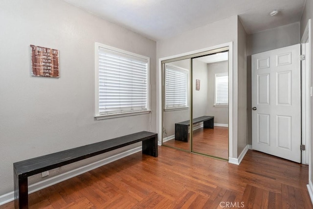 unfurnished bedroom with dark parquet flooring and a closet