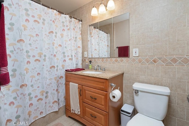 bathroom featuring a shower with shower curtain, vanity, toilet, and tile walls