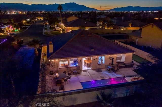 back house at dusk with a patio and a mountain view