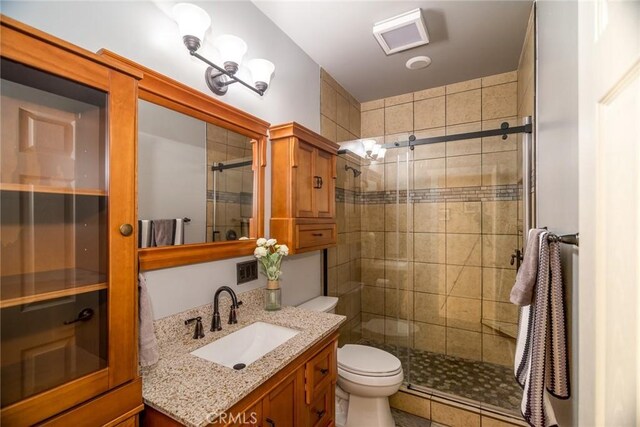 bathroom with vanity, a shower with shower door, and toilet