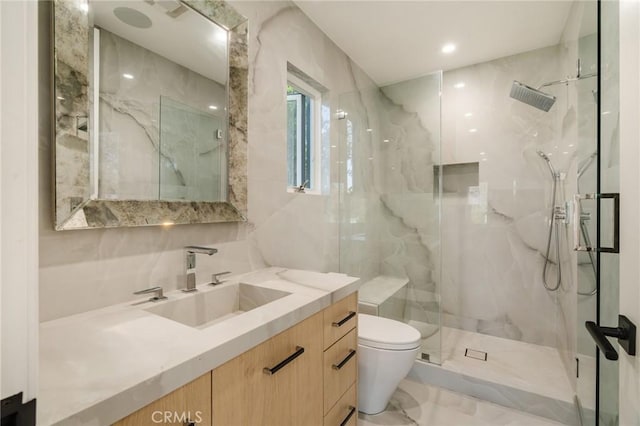 bathroom with tiled shower, vanity, tile walls, and toilet