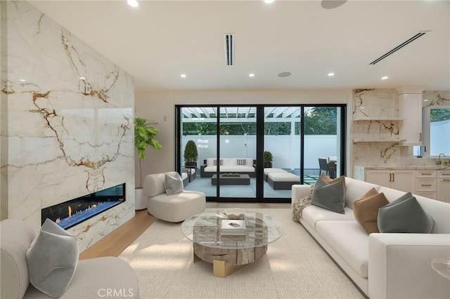 living room with a premium fireplace, sink, and light hardwood / wood-style flooring